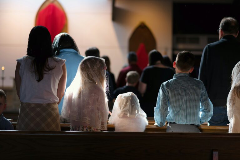 Children and adults standing in church pews during Catholic Mass.